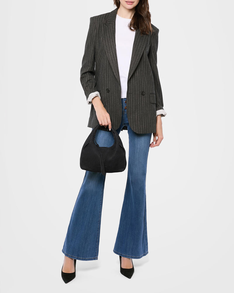 A woman wearing a black blazer, white shirt and jeans, showing off this small purse. The mini bag is filled with everything she needs for the day. 