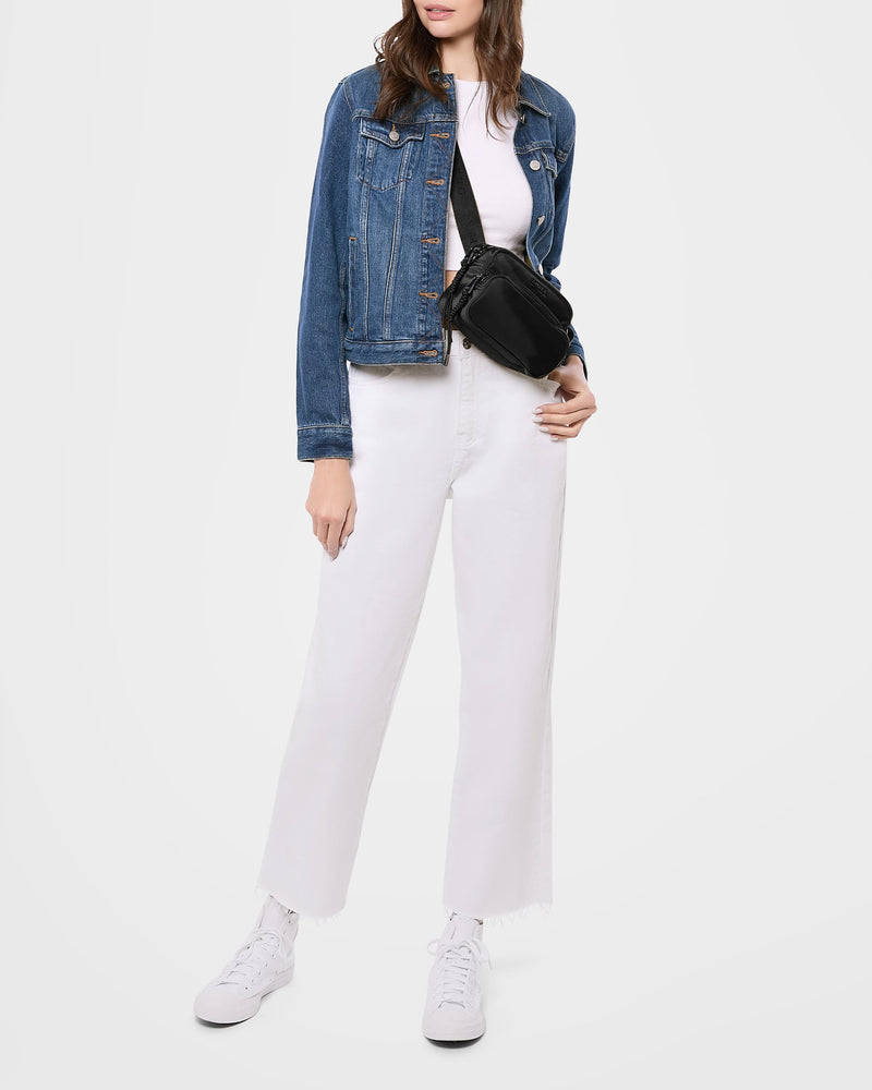 A woman wearing denim jacket with a white shirt and pants, showcasing this nylon bag as a crossbody.